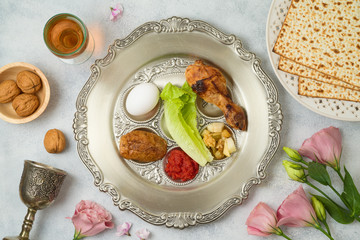 Jewish holiday Passover background with matzo, seder plate and spring flowers.