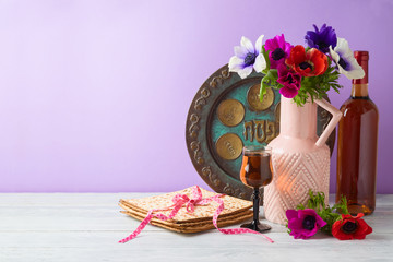 Jewish holiday Passover background with flowers, wine, matzo and seder plate on wooden table
