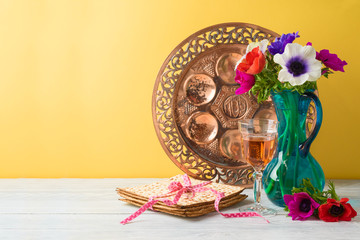 Jewish holiday Passover background with flowers, wine, matzo and seder plate on wooden table