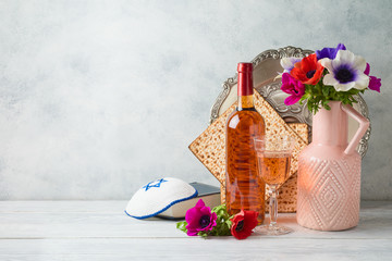 Jewish holiday Passover background with flowers, wine, matzo and seder plate on wooden table