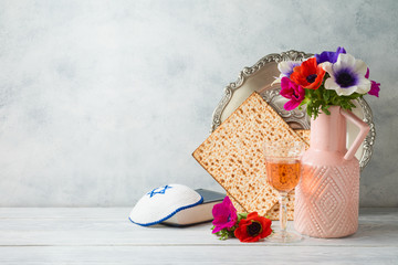 Jewish holiday Passover background with flowers, wine, matzo and seder plate on wooden table