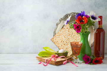 Jewish holiday Passover background with flowers, wine, matzo and seder plate on wooden table
