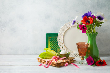 Jewish holiday Passover background with flowers, wine, matzo and seder plate on wooden table