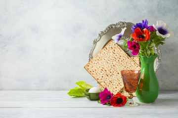 Jewish holiday Passover background with flowers, wine, matzo and seder plate on wooden table