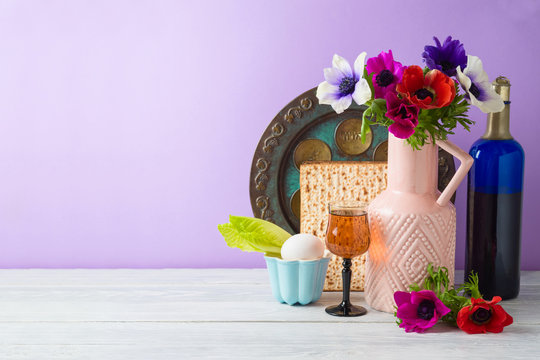 Jewish holiday Passover background with flowers, wine, matzo and seder plate on wooden table