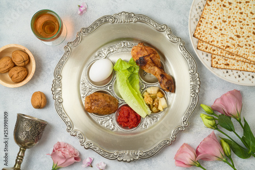 Jewish holiday Passover background with matzo, seder plate and spring flowers.