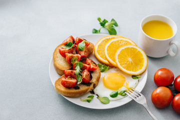Breakfast of eggs and sandwiches with tomatoes and orange juice close up