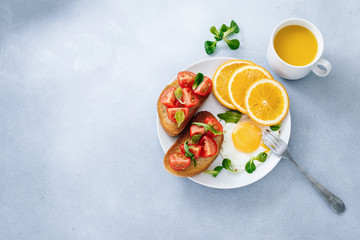 Breakfast of eggs and sandwiches with tomatoes and orange juice top view