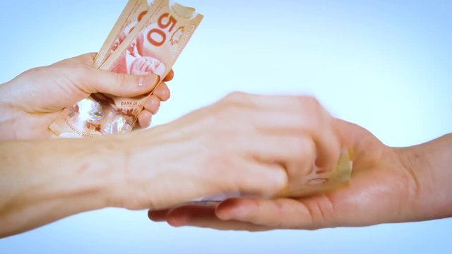 Female hand counts out bills to male hand after a gimme hand gesture