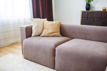 Relaxation concept. Two cushiong lying on brown sofa in modern interior