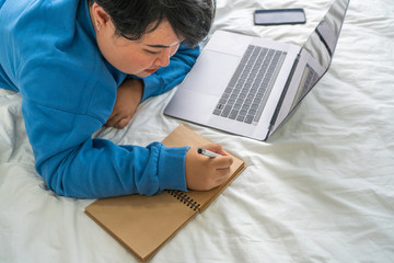 Naklejka premium Asian woman lying on bed and writing diary