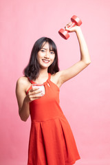 Healthy Asian woman drinking a glass of milk and dumbbell.