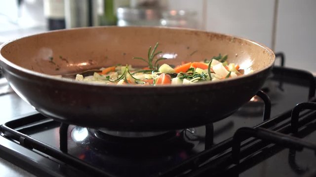 Close-up of a pan filled with mixed colorful vegetables sizzling in butter, restaurant kitchen