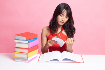 Young Asian woman read a book with books on table.