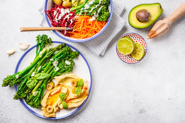 Vegan lunch concept. Rainbow vegetable salad and broccolini with hummus.