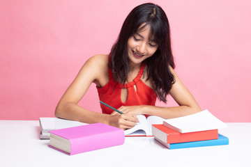 Young Asian woman read a book with books on table.