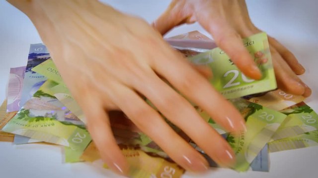 Female Hands Amassing A Pile Of Canadian Money And Sliding Off The Side