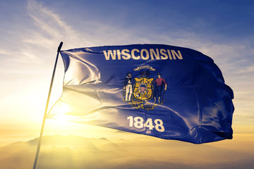 Wisconsin state of United States flag waving on the top sunrise mist fog - obrazy, fototapety, plakaty