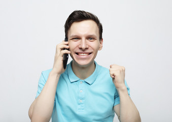 Happy young man in shirt gesturing and smiling while talking on the mobile phone