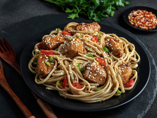 Asian noodles with chicken teriyaki , sesame,  rustic stone background. Closeup.  Chinese/Japanese noodles