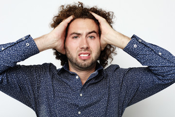 Close up of frustrated young man with head in hand against white background