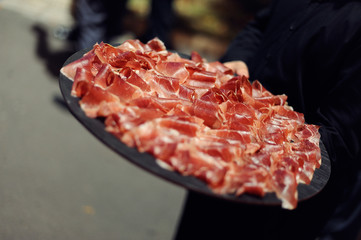 Jamón de bellota presentado en plato sujeto por camarero