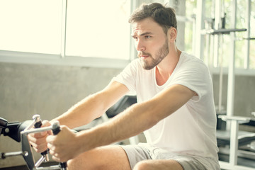 Naklejka na ściany i meble Portrait Caucasian handsome young man Are building muscles with exercise machines,healthy sports lifestyle, Fitness concept