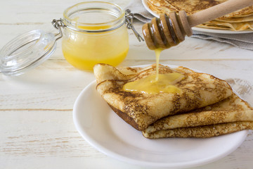 Russian pancakes Bliny with honey on white wooden rustic background. Copy space