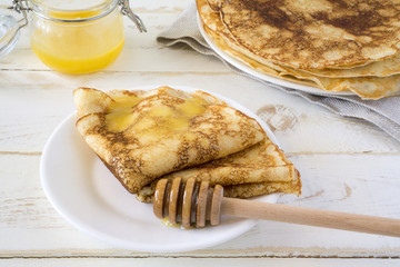Russian pancakes Bliny with honey on white wooden rustic background. Copy space