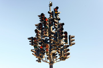 Traffic light tree with lots of lamps under the sky.