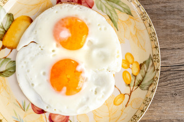Closeup of Two fried eggs in the colorful plate.