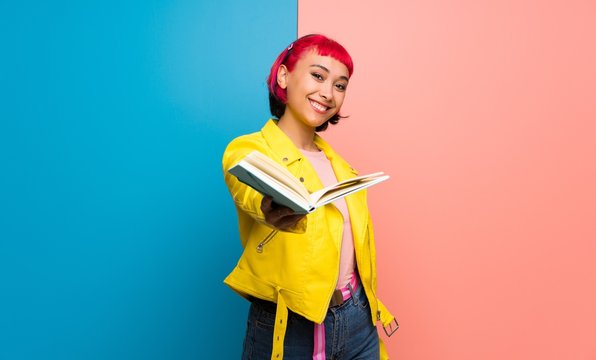 Young woman with yellow jacket holding a book and giving it to someone