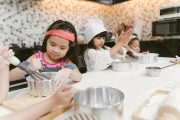 Group of kids are preparing the bakery in the kitchen .Children learning to cooking cookies