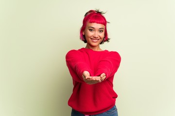Young woman with red sweater holding copyspace imaginary on the palm to insert an ad