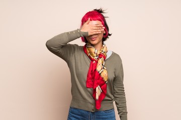 Young woman with pink hair over yellow wall covering eyes by hands. Do not want to see something