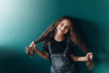 Teen pretty cute caucasian girl posing at home on green wall background. Beauty, childhood, emotions concept