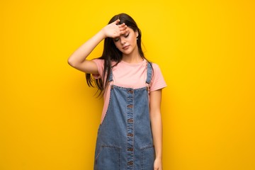 Teenager girl over yellow wall with tired and sick expression