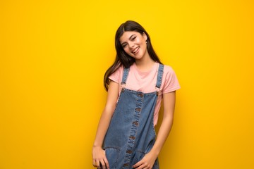 Teenager girl over yellow wall smiling