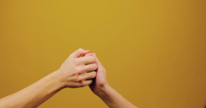 A man gives a hand to a woman. The girl reciprocates the guy. Isolated, yellow background, studio, trust, reliability, love.