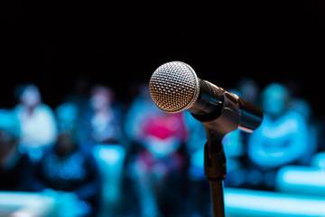 Wireless microphone on the stand. Blurred background. People in the audience. Show on stage in the...