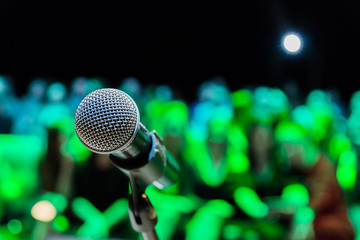 Wireless microphone on the stand. Blurred background. People in the audience. Show on stage in the theater or concert hall.