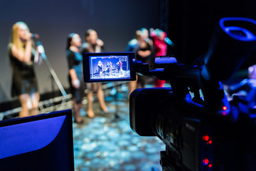 Video recording of the concert. Girls sing in microphones. Camcorder with LCD display. Shooting in the interior, Studio or on stage.