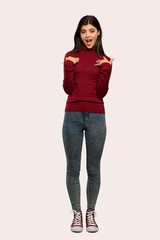 A full-length shot of a Teenager girl with turtleneck with surprise facial expression over isolated background