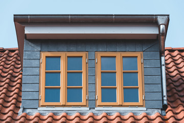 pair of dormer windows on a roof with red tiles