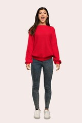 A full-length shot of a Teenager girl with red sweater with surprise facial expression over isolated background