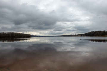 riverside landscape in latvia with dark water and dirty shore line