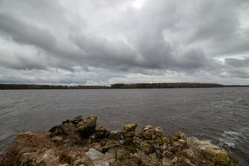 riverside landscape in latvia with dark water and dirty shore line