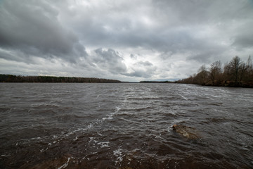 riverside landscape in latvia with dark water and dirty shore line