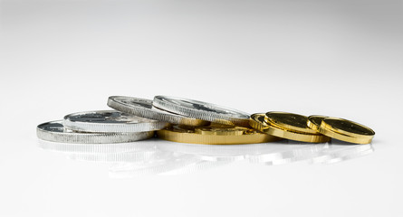 Gold and silver coins in close up isolated on light gray background.