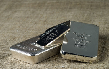 Several different silver bullion against the background of the texture of coarse cloth.